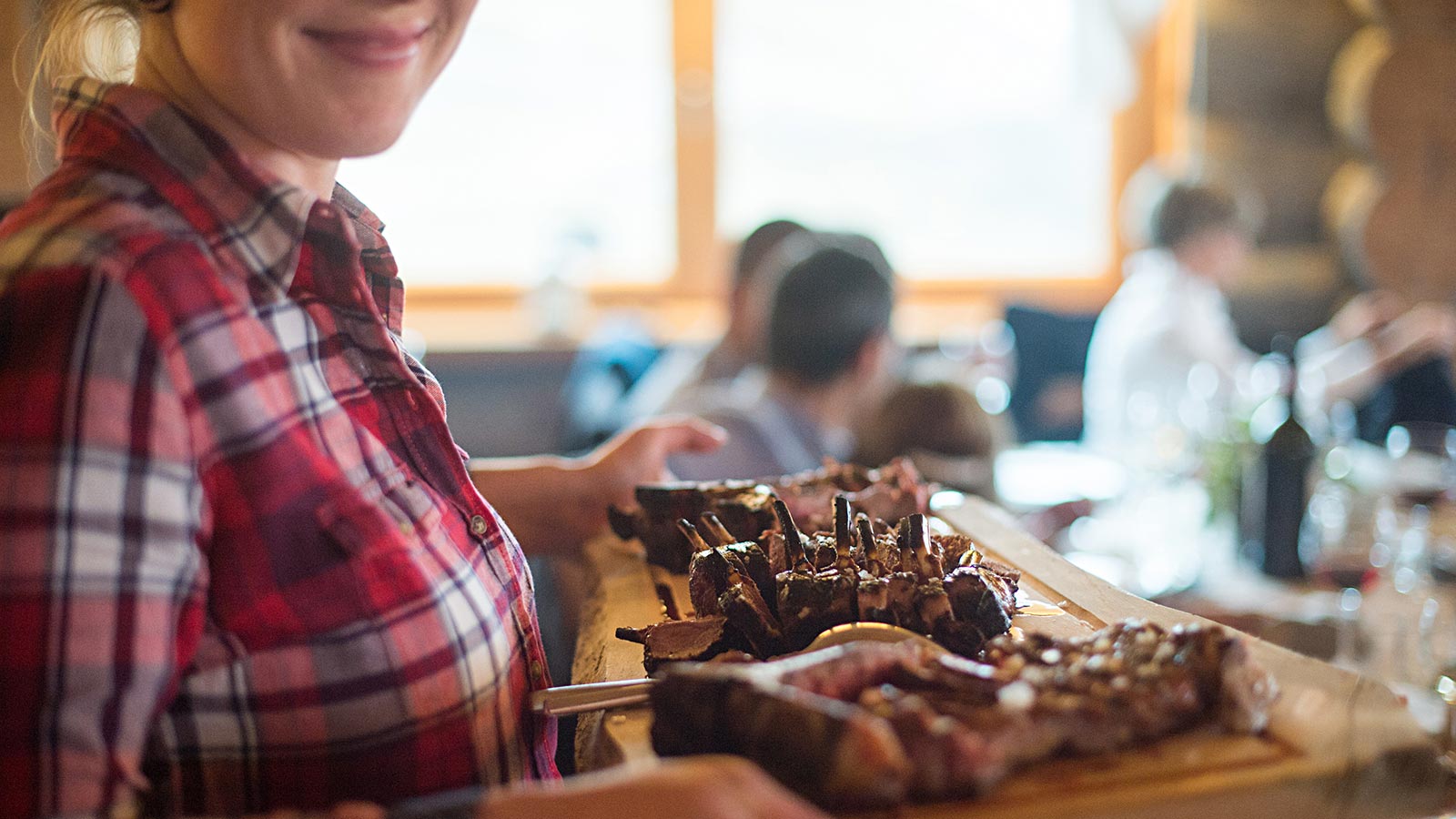 Woman serves wooden chopping board with beef ribs
